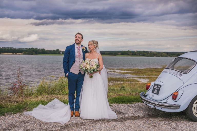 Married couple by sea with blue VW Beetle